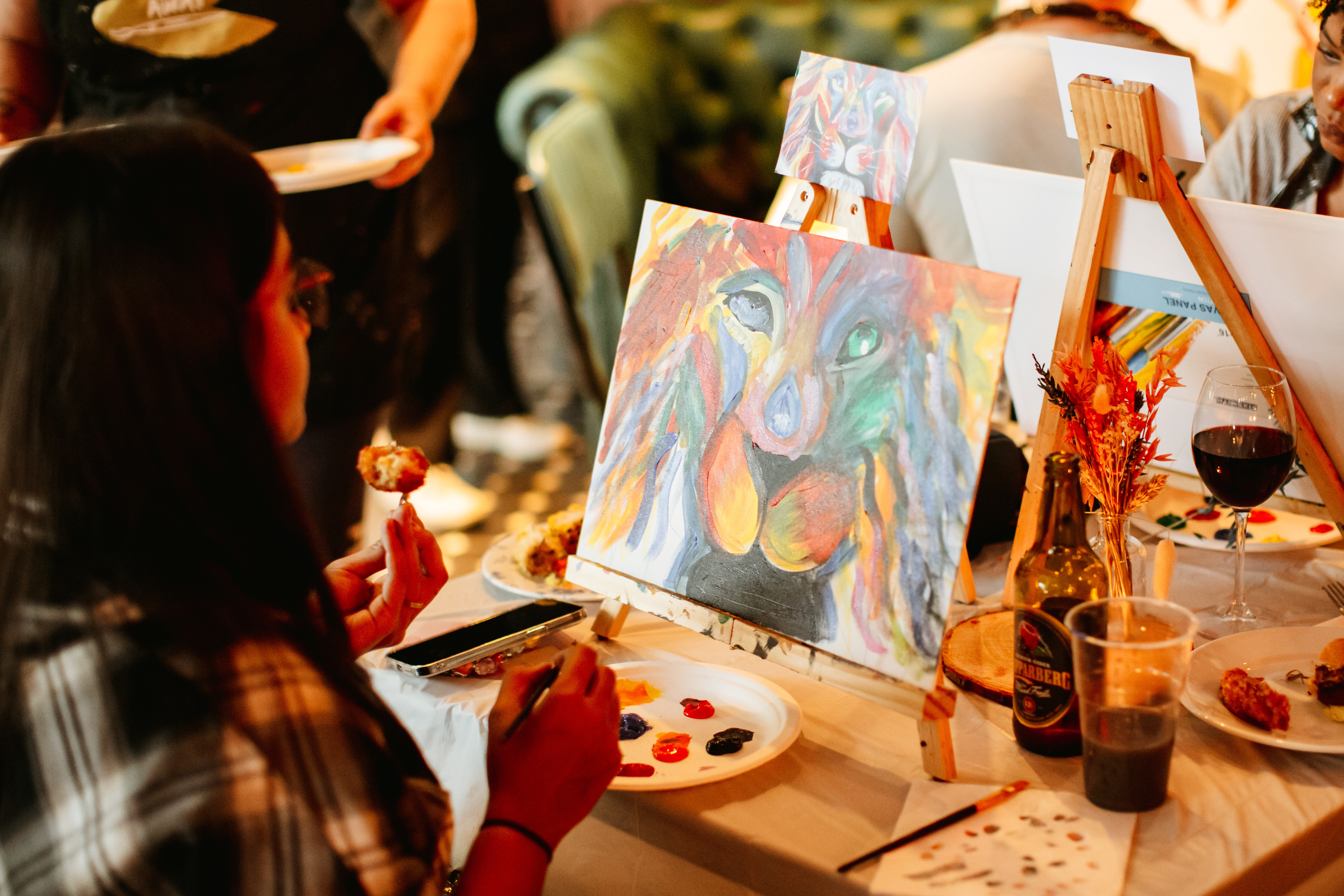 Woman sitting in front of a canvas with a colourful lion painting on it